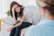stock-photo-42790622-worried-woman-sitting-and-looking-at-her-therapist